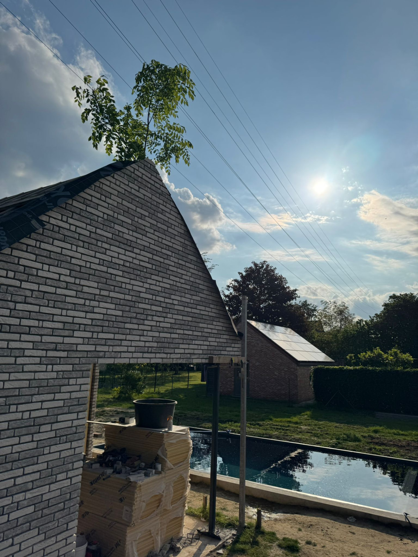 Zijgevel van het poolhouse in aanbouw met zicht op het zwembad