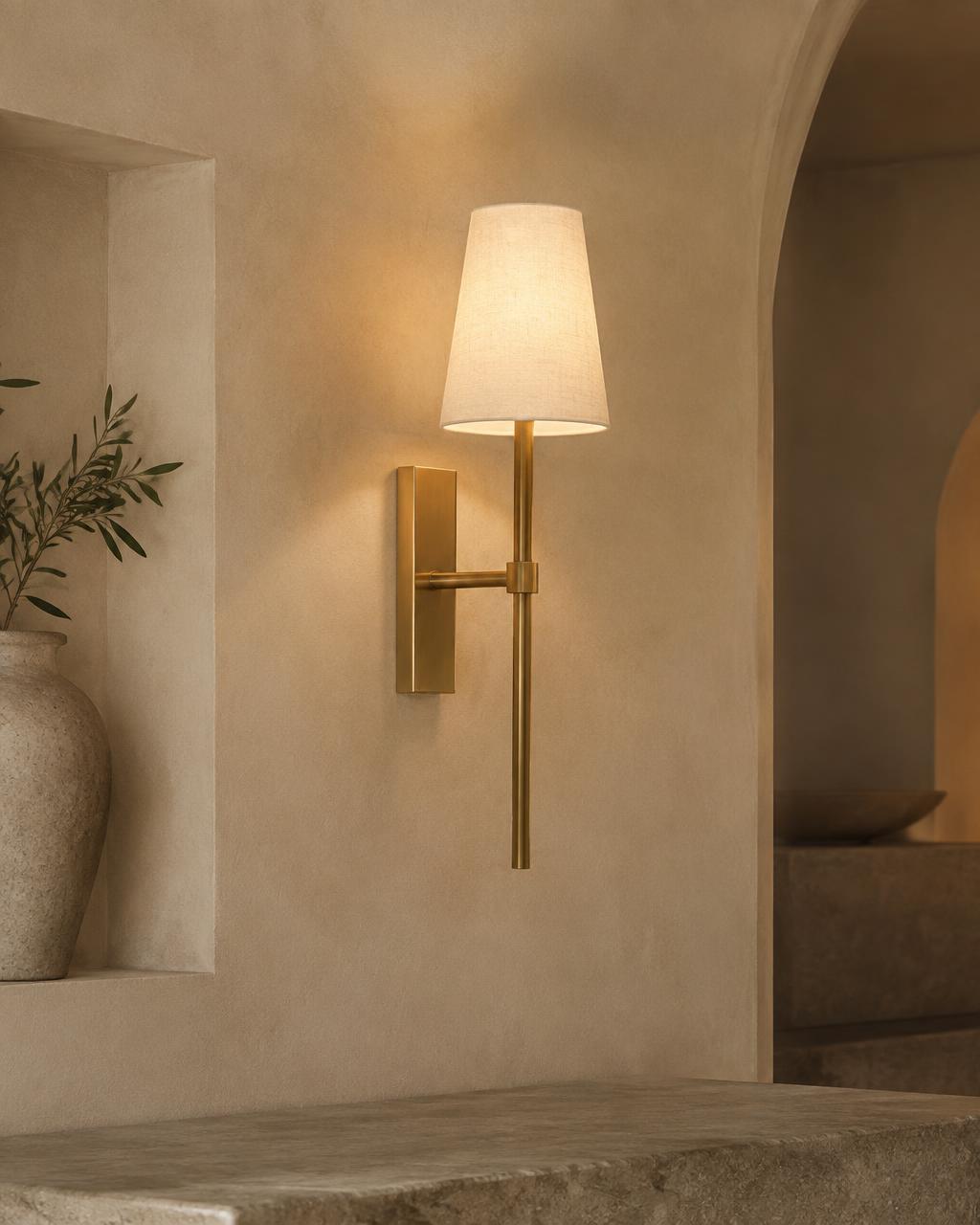 Messing wandlamp met linnen kap op een kalkwand